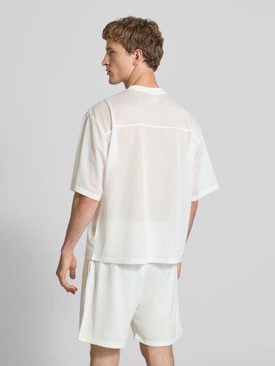 Männermodel trägt T-Shirt aus Mesh mit Logo-Print von REVIEW, Herren T-Shirt in Weiß, Loose-Fit, Rundhalsausschnitt, Rückenlänge 66 cm, Ganzkörperansicht Rückansicht.