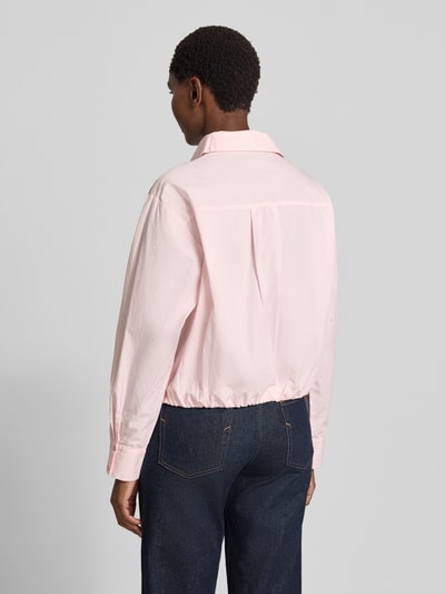 Frauenmodel trägt Regular Fit Hemdbluse aus reiner Baumwolle Modell 'Emmana' von Neo Noir in zartem Rosa mit langem Arm, Rückenansicht. 1-Knopf-Manschetten, elastischer Saum, Hemdblusenkragen, durchgehende Knopfleiste, Rückenlänge 53 cm, Ärmellänge 64 cm.