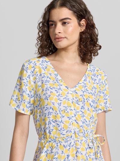 Frauenmodel trägt A-Linien Midikleid aus reiner Viskose Modell 'BARRI' von Pieces mit Optik:Allover-Muster in Gelb und Blau, Nahaufnahme Oberkörper. Passform: A-Linie, Länge Midi, Rundhals-Ausschnitt, Verschluss: Knopf, Ärmelform: Ohne, Saum: Gerade, Material: Reine Viskose.
