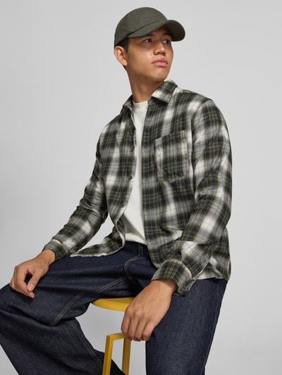 Männermodel trägt Slim Fit Freizeithemd aus reiner Baumwolle Modell 'James' von JACK & JONES, kariert, Brusttasche, Langarm, Ganzkörperansicht von vorne.