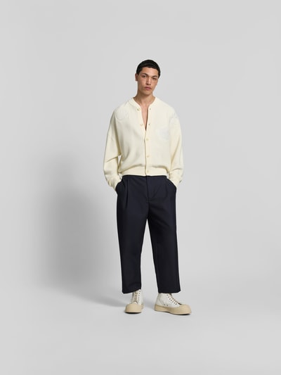 Männermodel trägt Straight Fit Stoffhose mit Bundfalten von MAISON KITSUNÉ aus Reine Baumwolle in Dunkelblau mit Haken- und Reißverschluss, verkürzte Passform, Ganzkörperansicht von vorne.