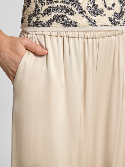 Frauenmodel trägt Wide Fit Hose mit elastischem Bund von Comma aus beigefarbenem Material-Mix mit Viskose-Anteil und Eingrifftaschen, Nahaufnahme Oberkörper.