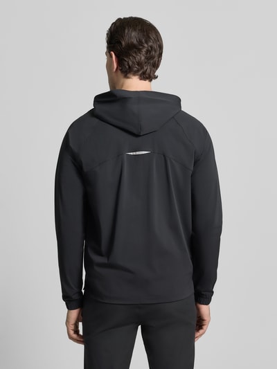 Mannenmodel draagt zwarte Trainingsjacke met Kapuze Modell 'THE ONE JACKET' van Fabletics, reflecterend logo, rugaanzicht.