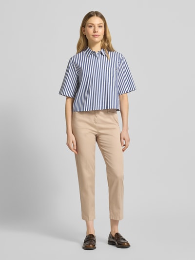 Frauenmodel trägt Hose in verkürzter Passform Modell 'Mara S' von Brax, Beige, Baumwoll-Elasthan-Mix, Bügelfalten, Ganzkörperansicht von vorne.