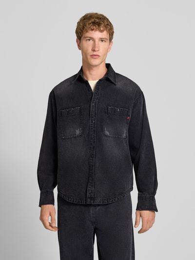 Männermodel trägt Regular Fit Jeanshemd aus reiner Baumwolle von Replay in Schwarz mit Kentkragen und Brusttaschen, Nahaufnahme Oberkörper.