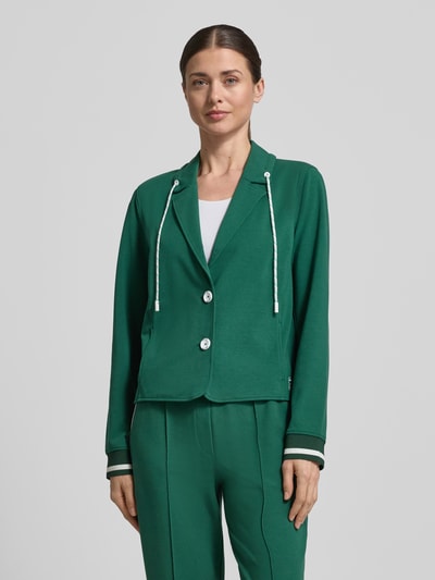 Kobieta modelka nosi Regular Fit Blazer mit Eingrifftaschen od Marc Cain, zielony bawełna-modal, krój regular fit, guziki, tunel przy kołnierzu, elastyczne mankiety, długość pleców w rozmiarze 36: 55 cm, szerokość w rozmiarze 36: 49 cm, długość rękawa w rozmiarze 36: 63 cm, widok całej sylwetki z przodu.