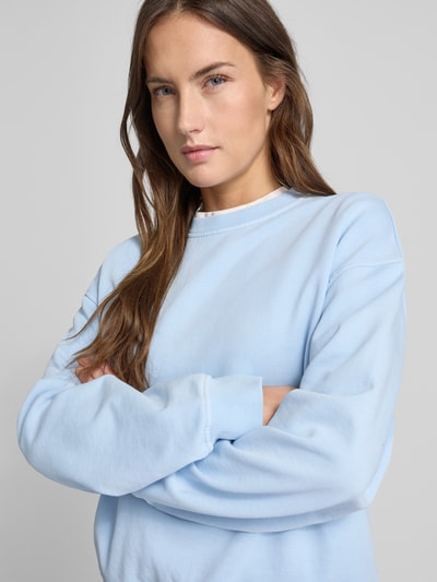 Modelka kobieca nosi Oversized Sweatshirt mit gerippten Abschlüssen Modell 'SAVAN' od Samsøe Samsøe, bawełna, kolor jasnoniebieski, zbliżenie na górną część ciała z przodu.