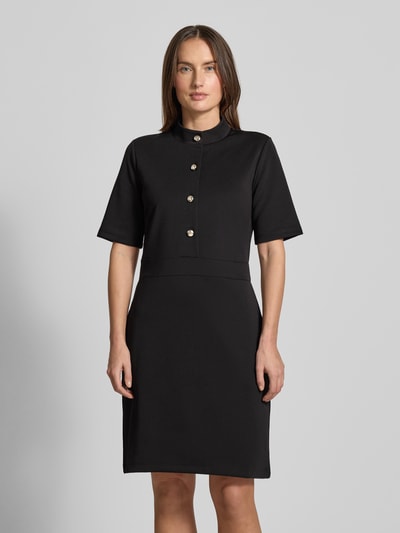 Frauenmodel trägt Kleid mit Stehkragen und Knopfleiste Modell 'Tibra' von JOOP!, Material-Mix mit Baumwoll-Anteil, A-Linie, Mini, 1/2-Arm, schwarze Farbe, glatte Textur, Ganzkörperansicht von vorne.
