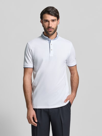Męski model nosi Regular Fit Poloshirt aus reiner Baumwolle mit Stehkragen von Christian Berg Men, biały, gładka tekstura, listwa guzikowa, krótkie rękawy, elastyczne zakończenia rękawów, długość tyłu 75 cm w rozmiarze M, całkowity widok z przodu.
