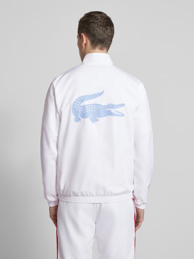 Männermodel trägt Regular Fit Trainingsanzug mit Kontraststreifen von Lacoste Sport in Weiß mit Logo-Applikation, Ganzkörperansicht Rückansicht.