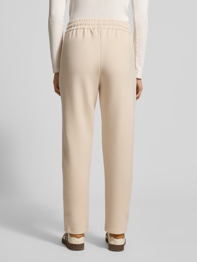 Frauenmodel trägt Sweatpants mit elastischem Bund Modell 'Twinka' von JOOP! aus Material-Mix mit Modal-Anteil, Regular-Fit, Label-Stitching, Tunnelzug, cremefarben, Ganzkörperansicht Rückansicht.