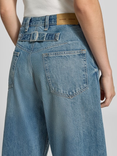 Frauenmodel trägt Wide Fit Jeans aus reiner Baumwolle Modell 'Sahar' von Samsøe Samsøe in Blau, 5-Pocket-Design, Ganzkörperansicht Rückansicht.