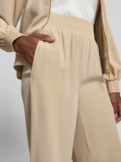 Frauenmodel trägt Stoffhose mit Eingrifftaschen von Joseph aus Acetat-Mix in Beige, lockere Passform, Ripp-Optik am Bund, Nahaufnahme Oberkörper.