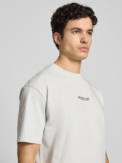 Männermodel trägt Oversized T-Shirt aus Reine Baumwolle Modell 'Stavoren' von Pegador, Halbarm, Rundhalsausschnitt, Label-Detail, Nahaufnahme Oberkörper.