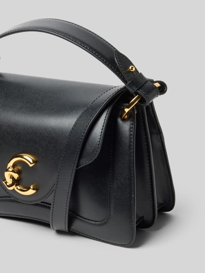Produktfoto, Handtasche met labeldetail van Coccinelle in zwart met goudkleurige details, hoofvak met omslag, draagband, schouderband, binnenvak met ritssluiting, breedte 18 cm, lengte 16 cm, diepte 11 cm, bandlengte 102 cm.