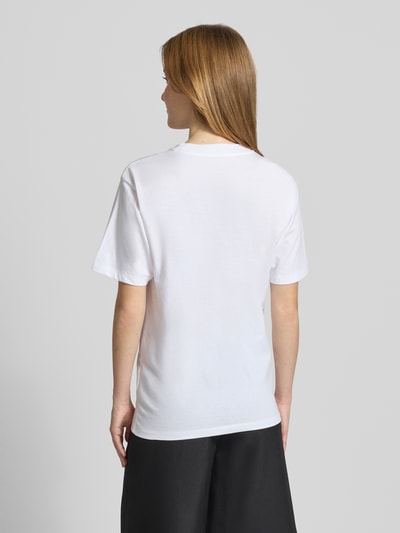 Frauenmodel trägt T-Shirt mit Brusttasche und Label-Detail von Carhartt Work In Progress aus Reine Baumwolle, Regular-Fit, Rückenlänge bei Größe S 59 cm, Ganzkörperansicht Rückansicht.
