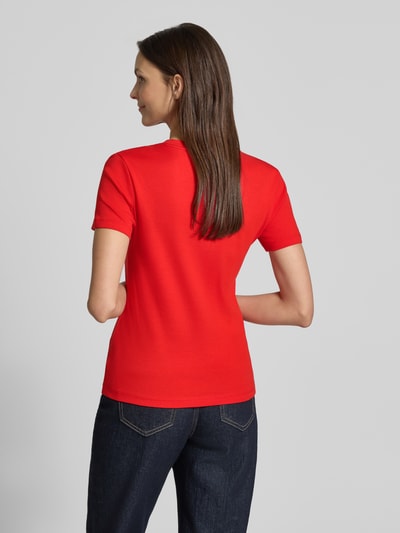 Modelka nosi Slim Fit T-Shirt aus reiner Baumwolle von Tommy Hilfiger, czerwony, gładki jersey, logo, krótki rękaw, widok z tyłu, pełna sylwetka.