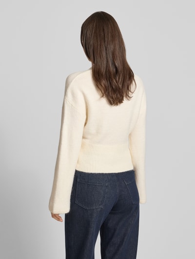 Frauenmodel trägt Strickpullover mit weiten Ärmeln Modell 'Stella' von Gina Tricot, cremefarben, Material-Mix mit Alpaka-Anteil, Regular-Fit, Rundhalsausschnitt, Rückenlänge bei Größe S 55 cm, Ärmellänge 60 cm, Ganzkörperansicht Rückansicht.