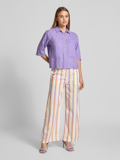 Frauenmodel trägt Regular Fit Leinenbluse mit Brusttaschen von Emily Van den Bergh in Lila, kombiniert mit gestreifter Hose, reine Leinenstruktur, Hemdblusenkragen, Knopfleiste, 3/4-Arm, Ganzkörperansicht von vorne.
