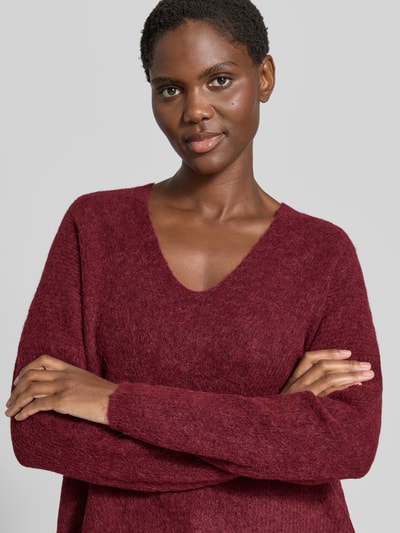 Frauenmodel trägt Strickpullover aus Woll-Mix mit V-Ausschnitt Modell 'THORA' von MOS MOSH in Bordeaux, Nahaufnahme Oberkörper, Regular Fit, feine Textur, Alpaka-Anteil, Damen Strickpullover, Rückenlänge 82 cm, Ärmellänge 46 cm.