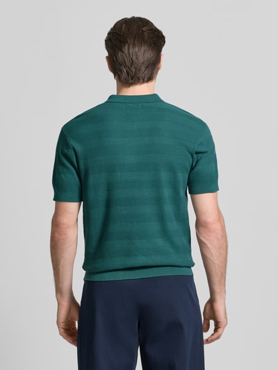 Männermodel trägt Slim Fit Poloshirt mit Logo-Stitching von Lerros in Grün, reine Baumwolle, strukturierte Oberfläche, Ganzkörperansicht Rückansicht.