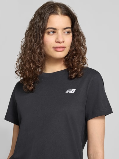 Frauenmodel trägt Regular Fit T-Shirt mit Logo-Stitching von New Balance aus reiner Baumwolle, Rundhalsausschnitt, Nahaufnahme Oberkörper. Rückenlänge bei Größe S: 60 cm.