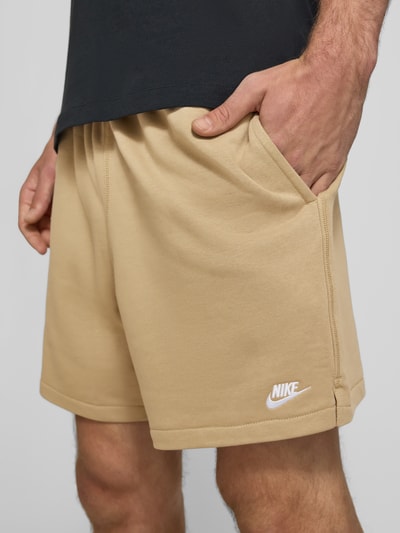 Männermodel trägt Regular Fit Sweatshorts aus Baumwoll-Mix von Nike in Beige mit weißen Details, Nahaufnahme Oberschenkel, Herren Sweatshorts von Nike.