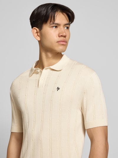 Männermodel trägt Slim Fit Strick-Poloshirt mit Label-Stitching von REVIEW, Reine Baumwolle, Zopfmuster, Knopfleiste, Nahaufnahme Oberkörper.