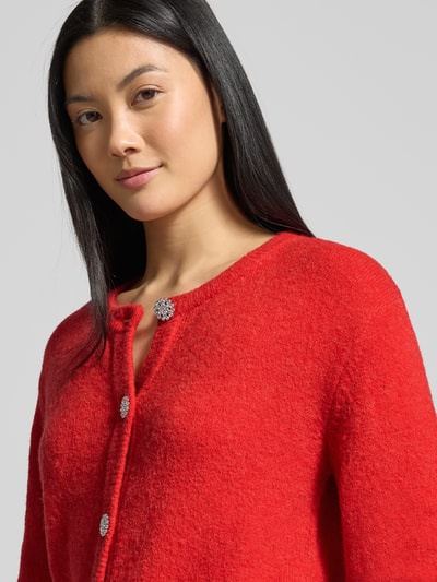 Frauenmodel trägt Strickjacke mit Knopfleiste Modell 'Hanni' von GUIDO MARIA KRETSCHMER WOMAN, Strukturmix in Rot, Nahaufnahme Oberkörper.