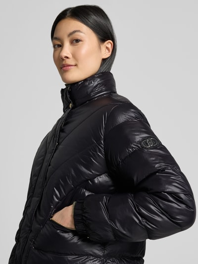 Frauenmodel trägt Regular Fit Jacke in Stepp-Optik Modell 'IMBOTTITO' von Liu Jo Sport in Schwarz, sichtbare Reißverschlusstaschen, Nahaufnahme Oberkörper. Rückenlänge, Schulterbreite, Brustweite und Ärmellänge beziehen sich auf Größe S.