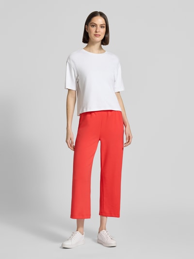 Frauenmodel trägt Wide Fit Sweatpants in verkürzter Passform Modell 'Banu' von Soyaconcept aus Elastischer-Material-Mix mit Baumwoll-Modal-Anteil in Rot, glatte Textur, elastischer Bund mit Tunnelzug, Ganzkörperansicht von vorne.
