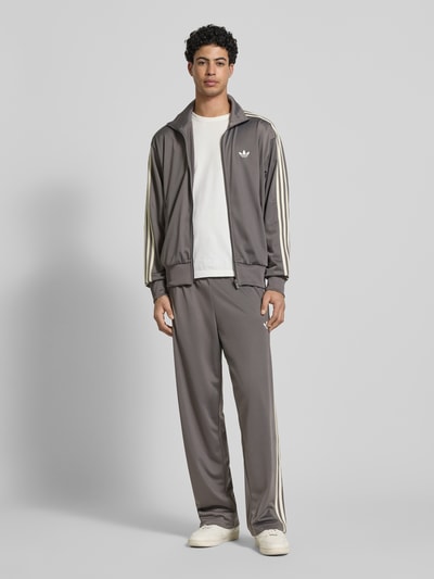 Männermodel trägt Regular Fit Sweatjacke mit Reißverschluss von adidas Originals, Optik: Unifarben, Kontraststreifen, Ganzkörperansicht von vorne.