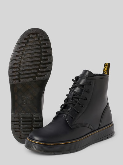 Produktfoto, schwarze Boots aus echtem Leder mit Label-Patch Modell 'Brookline Chukka' von Dr. Martens, Schnürverschluss, profilierte Sohle, abgerundete Passform, Absatzhöhe 4 cm, Schafthöhe 14 cm, Schaftweite 11 cm, Detailansicht mit strukturierter Oberfläche.