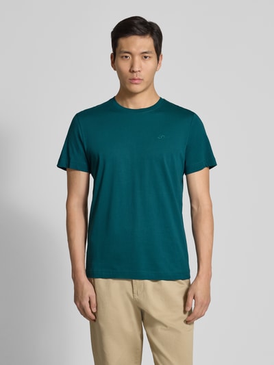 Mannenmodel draagt Regular Fit T-Shirt uit zuivere katoen van Tom Tailor in effen groen, rondhals, korte mouw, logo-stiksel, vooraanzicht bovenlichaam.