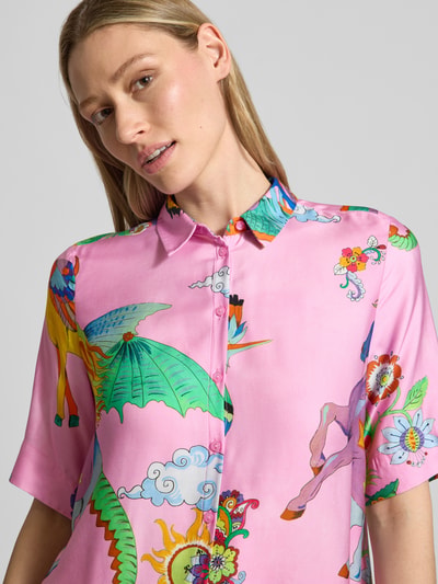 Kobiece modelka nosi Bluse aus Viskose mit Kentkragen od Milano Italy, wiskoza, krój straight fit, kołnierzyk typu kent, listwa guzikowa, długość tyłu w rozmiarze 36: 65 cm, długość rękawów w rozmiarze 36: 30 cm, różowe kolory z kolorowymi wzorami, gładka tekstura, detaliczna perspektywa, zbliżenie na górę ciała