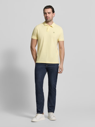 Männermodel trägt Slim Fit Poloshirt mit Logo-Stitching van MCNEAL in geel, katoen, polokraag, vooraanzicht volledige lichaamsopname.