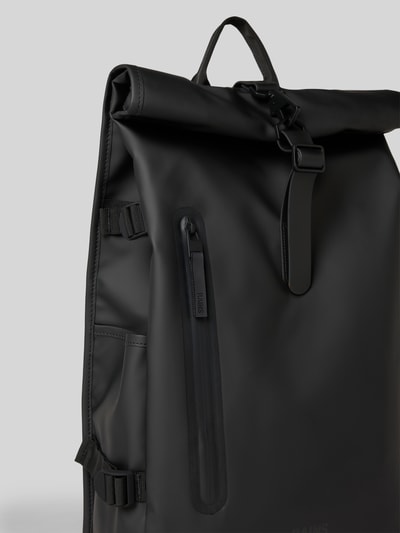 Produktfoto, Rolltop Rucksack mit Reißverschlusstasche von Rains in Schwarz mit Karabinerhaken, Tragehenkel, verstellbare Träger, Maße 31 cm Breite, 61 cm Länge, 15 cm Tiefe, Schulterriemen 74 cm.
