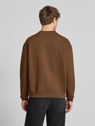 Männermodel trägt Sweatshirt mit Label-Print Modell 'TORREY' von DICKIES aus braunem Baumwoll-Mix, Lockerer-Schnitt, Gerippte-Abschlüsse, Ganzkörperansicht Rückansicht.
