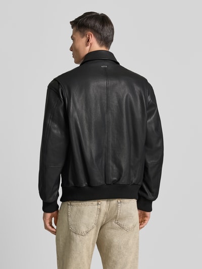 Męski model nosi Regular Fit Lederjacke aus echtem Ziegenleder Modell 'JOSUAL' von BOSS Orange, czarna, gładka faktura, Ganzkörperansicht Rückansicht.