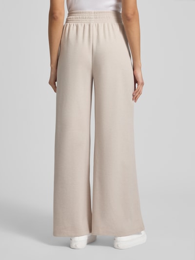 Männermodel trägt Wide Fit Stoffhose mit gelegten Falten von Christian Berg Woman, beżowy, materiał z bawełną, elastyczny pas, Ganzkörperansicht Rückansicht.