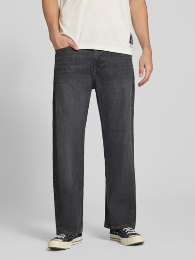 Männermodel trägt Wide Fit Jeans aus reiner Baumwolle Modell 'Ted' von JACK & JONES in Dunkelgrau, 5-Pocket-Design, Ganzkörperansicht von vorne.