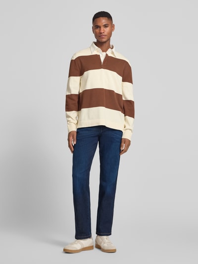 Männermodel trägt Straight Fit Jeans im 5-Pocket-Design Modell 'Texas' von Wrangler, dunkler Blauton, Baumwoll-Mix mit Stretch-Anteil, Gerader-Schnitt, Label-Detail, Knopf-Reißverschluss, Ganzkörperansicht von vorne.