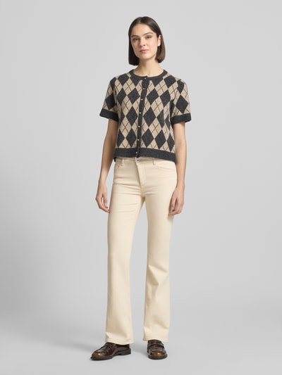 Frauenmodel trägt Flared Fit Jeans im 5-Pocket-Design Modell 'Shelby' von Mustang aus elastischem Baumwoll-Mix in Creme, Ganzkörperansicht von vorne.