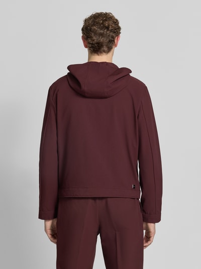 Männermodel trägt Jacke mit Kapuze und Zweiwege-Reißverschluss von Emporio Armani in Dunkelrot, Material-Mix mit Stretch-Anteil, Regular-Fit, Eingrifftaschen, Rückenlänge 66 cm, Schulterbreite 56 cm, Brustweite 58 cm, Ärmellänge 68 cm, Ganzkörperansicht Rückansicht.