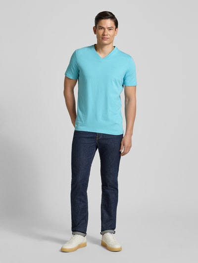 Męski model nosi Regular Fit T-Shirt aus reiner Baumwolle od s.Oliver RED LABEL, jednolity kolor, dżersej, krótki rękaw, dekolt w serek, aplikacja z metką, bawełna, widok całej sylwetki od przodu.