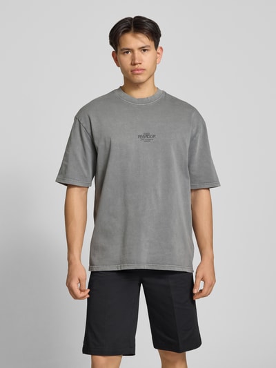 Męski model nosi Oversized T-Shirt mit 1/2-Arm Modell 'Trebic' od Pegador, bawełna, krój oversize, szary, okrągły dekolt, przód z detalem logo, Ganzkörperansicht von vorne.