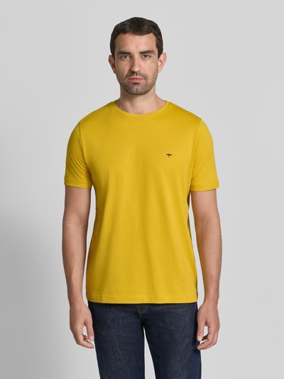Männermodel trägt T-Shirt mit Rundhalsausschnitt und Label-Stitching von Fynch-Hatton aus reiner Baumwolle in Gelb, Regular Fit, Ganzkörperansicht von vorne.