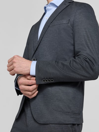 Męski model nosi Regular Fit Anzugsakko mit Viskose-Anteil von s.Oliver BLACK LABEL, wzór allover, krój regular fit, klapy z rewersami, zapięcie na dwa guziki, długi rękaw z kissing buttons, kieszeń na piersi, kieszeń wewnętrzna, naszywane kieszenie, odcień grafitowy, wyraźna faktura, zbliżenie na górną część ciała, zdjęcie z przodu.