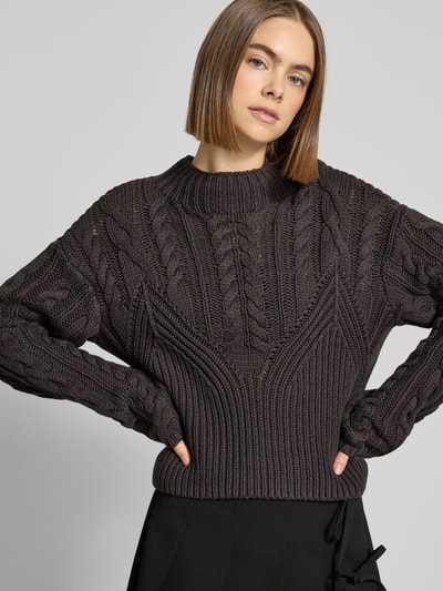 Frauenmodel trägt Slim Fit Pullover in strick-optik Modell 'Haysa' von Noisy May, mieszanka bawełny, okrągły dekolt, długa długość tyłu, czarny kolor, tekstura dzianiny, zakończenia rękawów, Ganzkörperansicht von vorne.