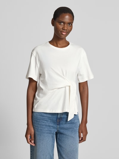 Frauenmodel trägt T-Shirt mit Knoten-Detail und Rundhalsausschnitt von Christian Berg Woman aus Reine Baumwolle im Regular-Fit, helle Farbe, Rückenlänge bei Größe S 55 cm, Ganzkörperansicht von vorne.